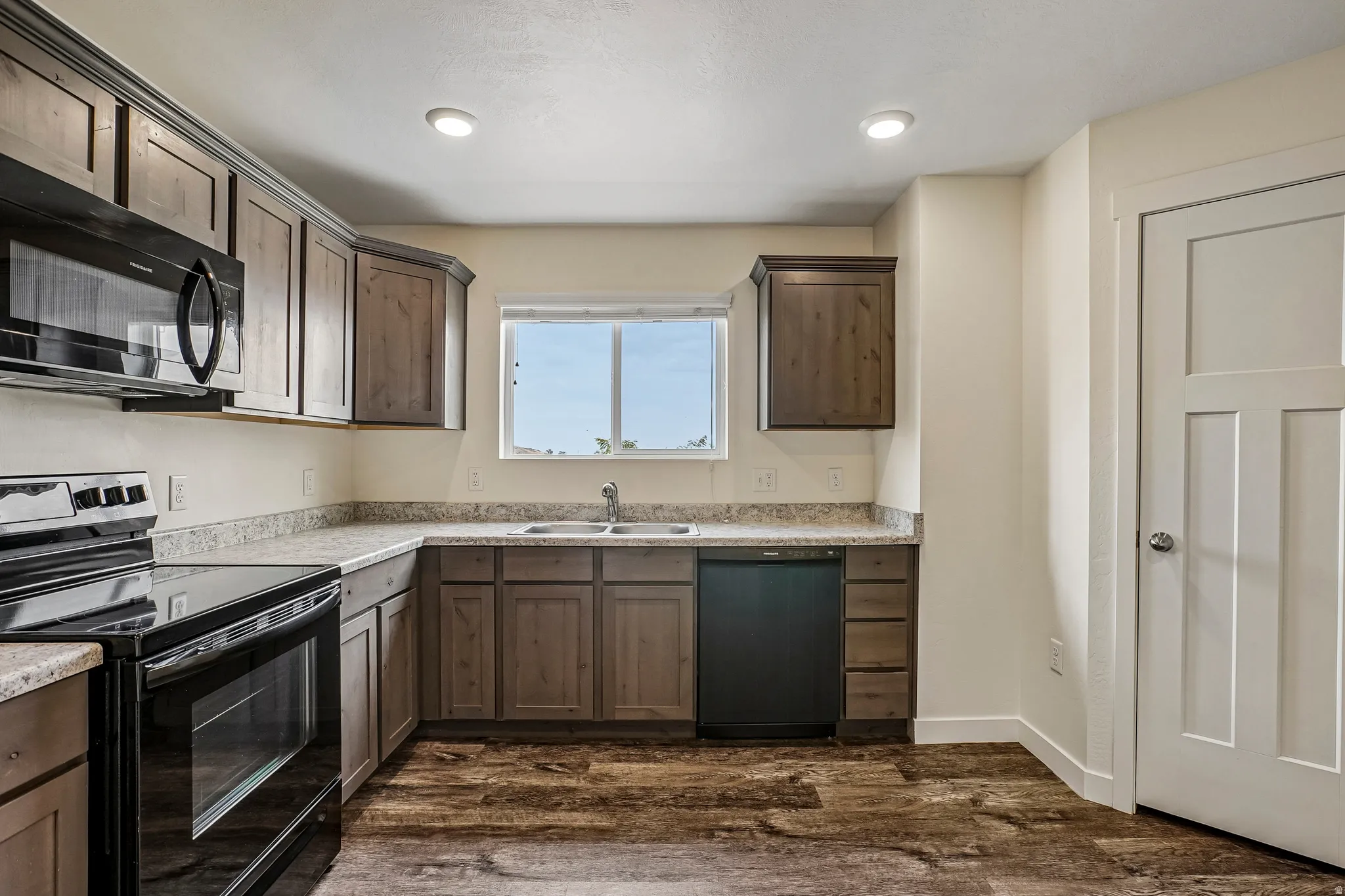 Kitchen featuring wood-finish cabinetry, light-toned countertops, and dark wood-finish flooring