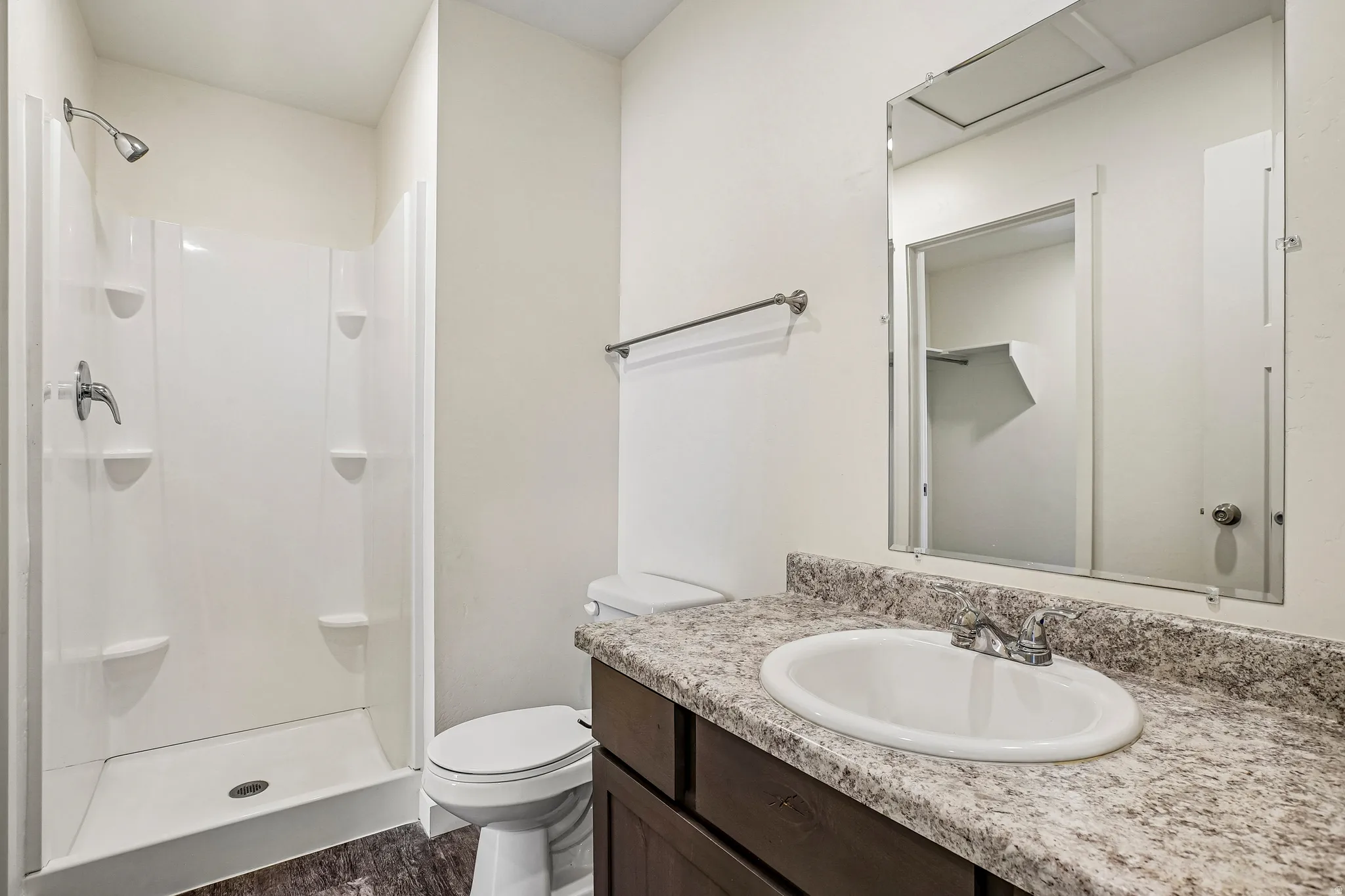 Spa-inspired bathroom featuring a granite-topped vanity with dual sink basins, framed mirror, and dark wood cabinetry