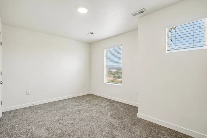Carpeted room featuring white walls, recessed ceiling lighting, and multiple windows with blinds