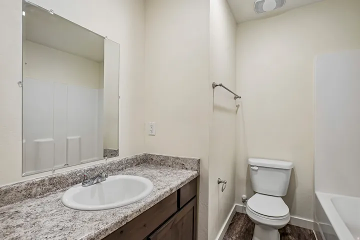 Bathroom vanity with an oval undermount sink and chrome faucet, set on a speckled countertop
