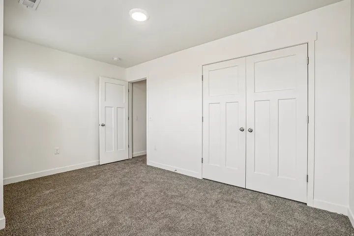 Neutral-toned room featuring a soft gray carpet, white walls, and a recessed ceiling light