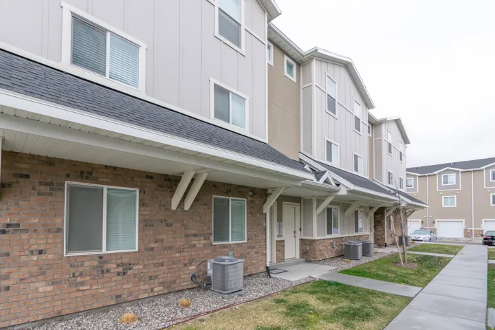 Contemporary townhome-style residences featuring a brick and siding facade, individual entryways, and covered porches