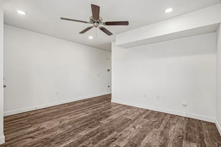 Spacious room featuring wood-finish flooring, recessed ceiling lighting, and a ceiling fan