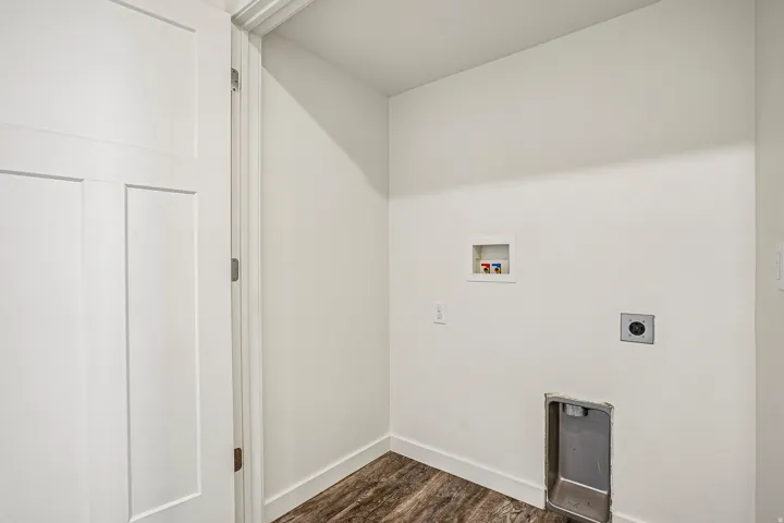 Dedicated utility space featuring wood-finish flooring, white walls, and a white interior door