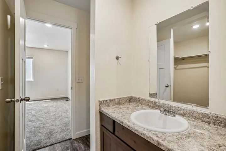 Bathroom vanity featuring a white oval undermount sink, chrome faucet, and speckled countertop