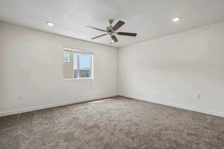 Expansive room featuring plush gray carpet and a contemporary ceiling fan