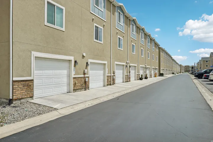 Exterior featuring stucco siding, stone accents, white garage doors, and individual concrete driveways