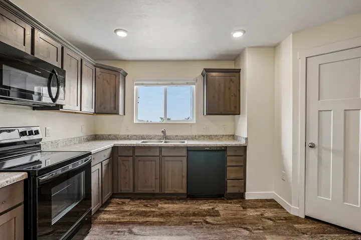 Kitchen featuring wood-finish cabinetry, light-toned countertops, and dark wood-finish flooring