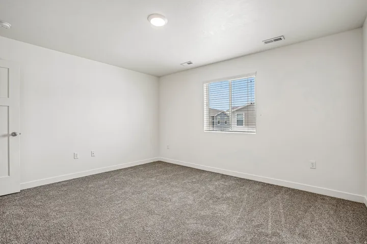 Spacious room featuring neutral carpet flooring, white walls, and a window with blinds