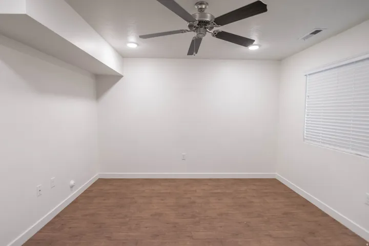 Room featuring light wood-finish flooring, white walls, and a window with horizontal blinds