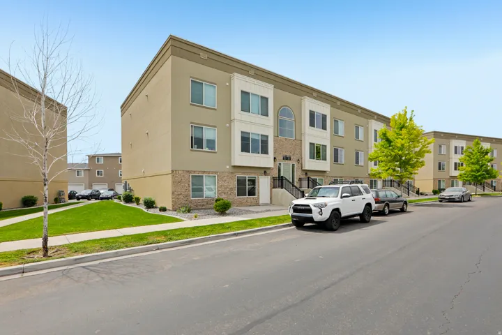 Multi-level townhome featuring a stucco and stone facade, private entrance, and front landscaping