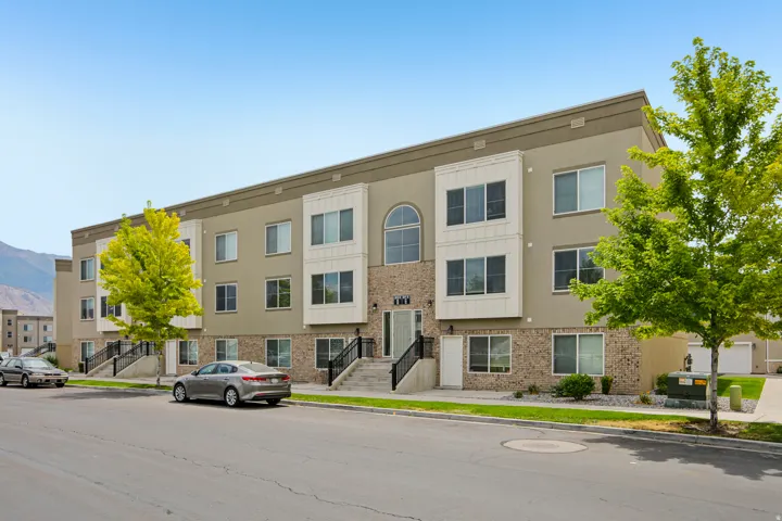 Contemporary townhome exterior featuring a multi-level design, neutral stucco siding, and a brick-finish facade