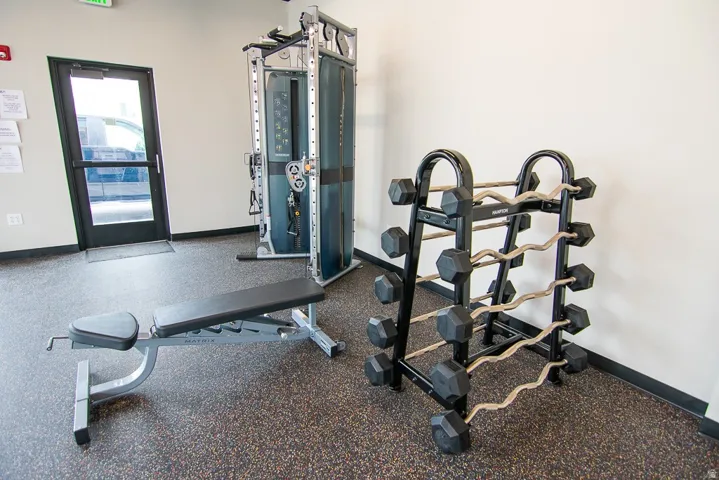 Dedicated fitness area featuring durable rubberized flooring, a full-length glass door, and white wall finishes