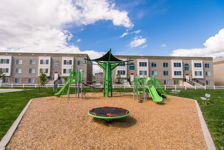 Community playground featuring a large playset with slides, climbing structures, and a shade canopy