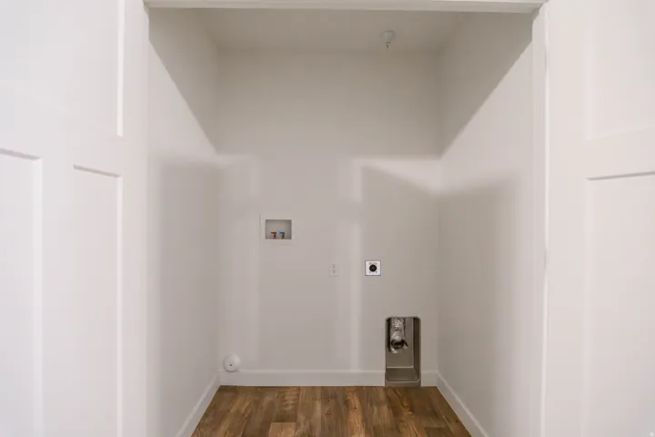 Dedicated laundry alcove featuring wood-finish flooring and white baseboards
