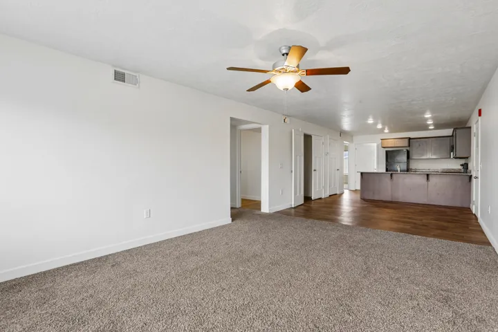 Open-concept living space featuring a ceiling fan with integrated lighting, recessed lighting, and a kitchen with dark cabinetry
