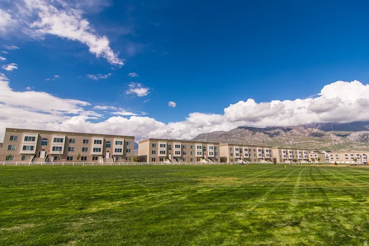 Expansive green space fronting multiple townhouse-style buildings with light-toned exteriors