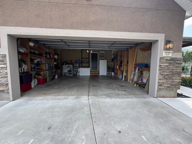 Integrated garage with concrete flooring and built-in storage shelving