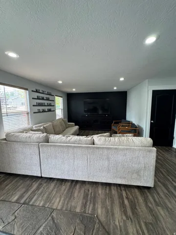 Recessed ceiling lighting, wood-finish flooring, accent wall, and wood window blinds