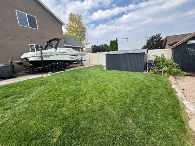 Expansive grass lawn with a metal storage shed and string lighting