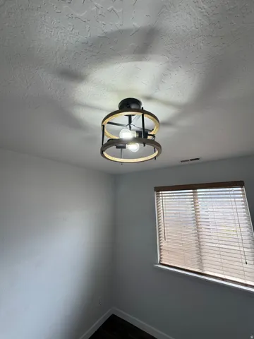 Ceiling fan with an industrial-style light fixture, window with blinds, and wood-finish flooring