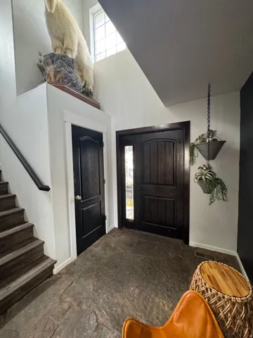 Distinguished entry with high ceilings, dark wood-finish entry door with sidelight, and natural stone flooring