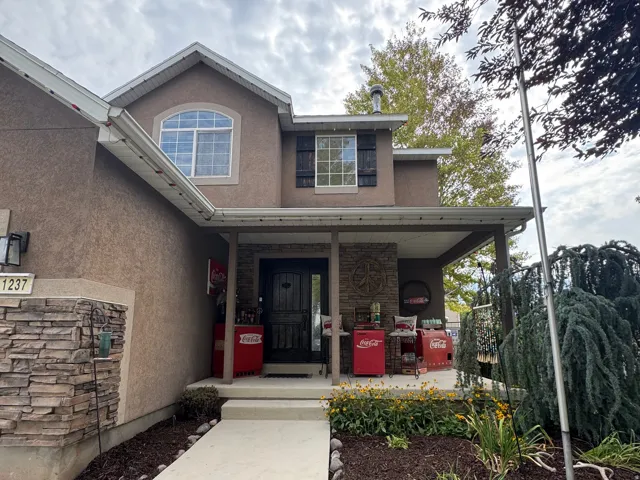 Stucco exterior with a covered front porch featuring stone-wrapped columns