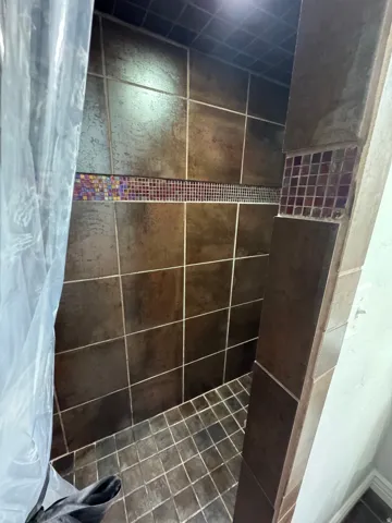 Tiled shower with decorative accent bands and recessed lighting