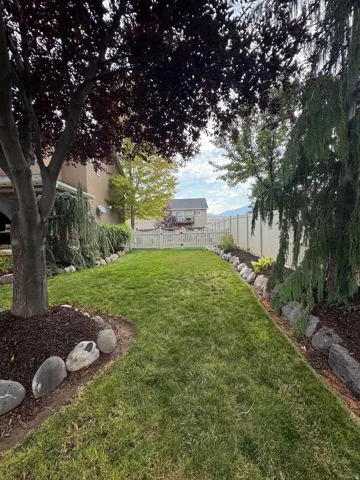 Expansive green lawn with mature trees and a white picket fence