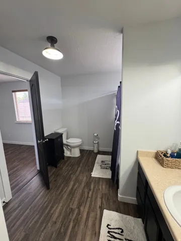Wood-finish flooring throughout, bright white walls, and a recessed ceiling light