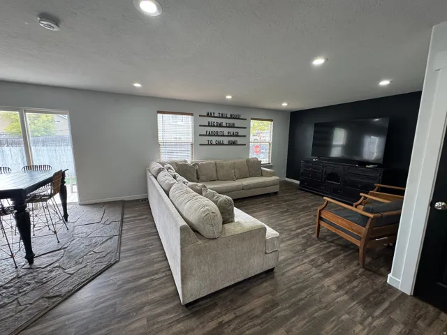 Recessed lighting, wood-finish flooring, sliding glass door, and a contrasting accent wall