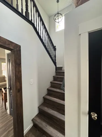 Dramatic open staircase featuring dark wood-finish treads, black metal railings, and soaring ceilings with natural light from above
