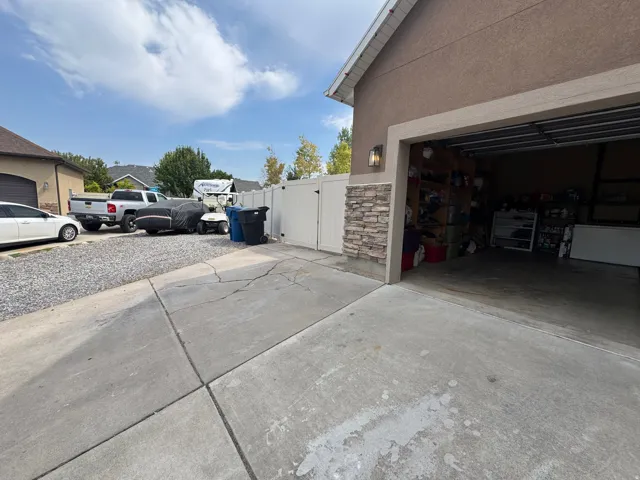 Stucco exterior with stone veneer accents, an attached garage, and a gravel parking area