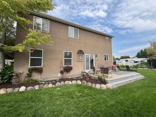 Expansive backyard featuring a large tiered deck, sliding glass door access, and a manicured lawn with a decorative stone border