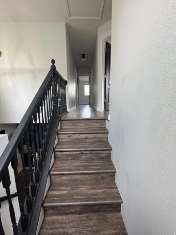 Staircase featuring wood-finish treads and a dark wood-finish handrail with balusters