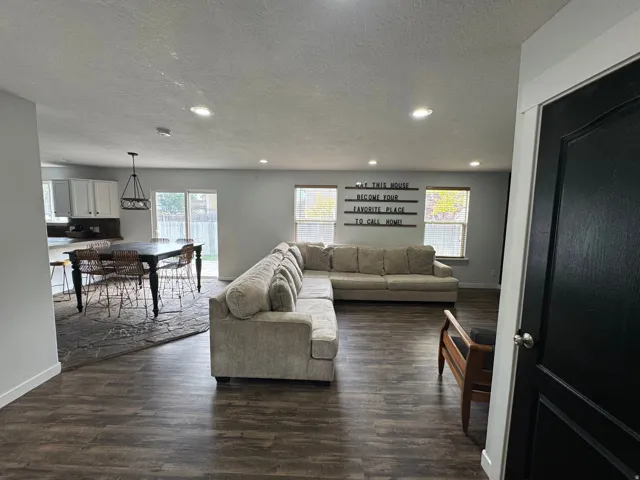 Open concept living area with wood-finish flooring, recessed lighting, and a sliding glass door