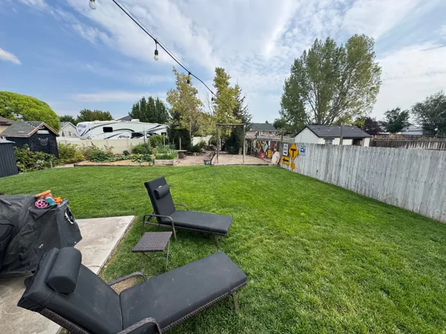 Expansive backyard featuring a manicured lawn, concrete patio, and a wood privacy fence