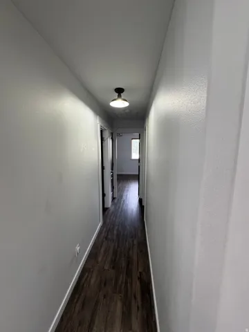 Hallway with wood-finish flooring and a flush-mount ceiling light