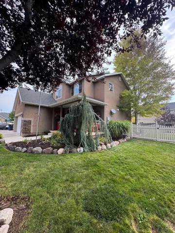 Two-story stucco exterior with a gabled roofline, stone facade accents, a front porch, and a fenced front yard