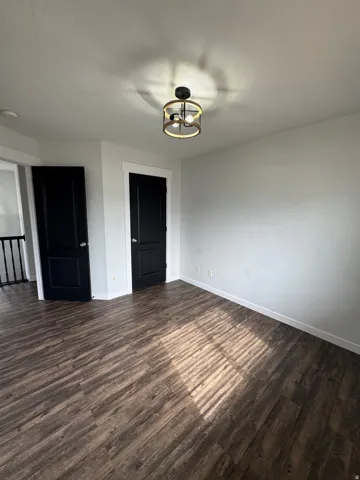 Hardwood-finish flooring, two panel doors, and a contemporary flush mount light fixture