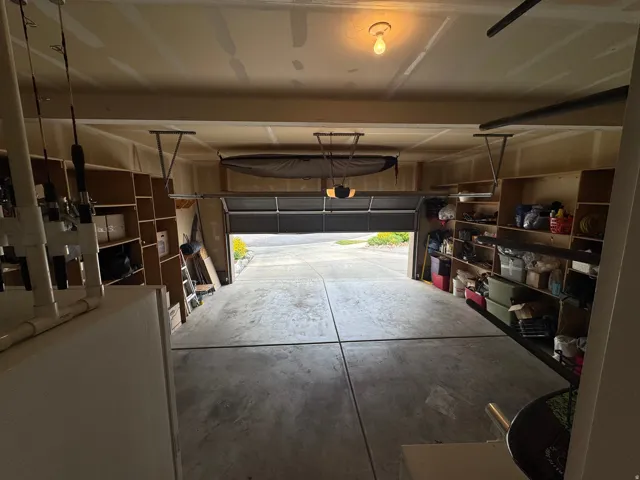 Attached garage with concrete flooring, built-in shelving, and an automatic garage door opener