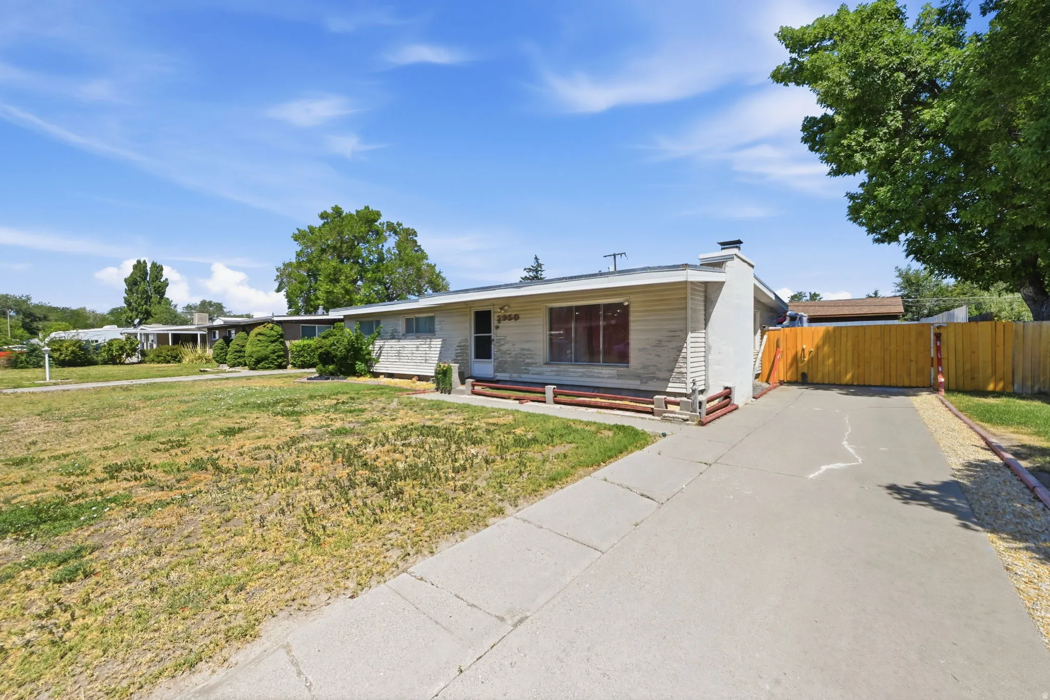 Single-story residence featuring a front yard, paved driveway, and perimeter fencing