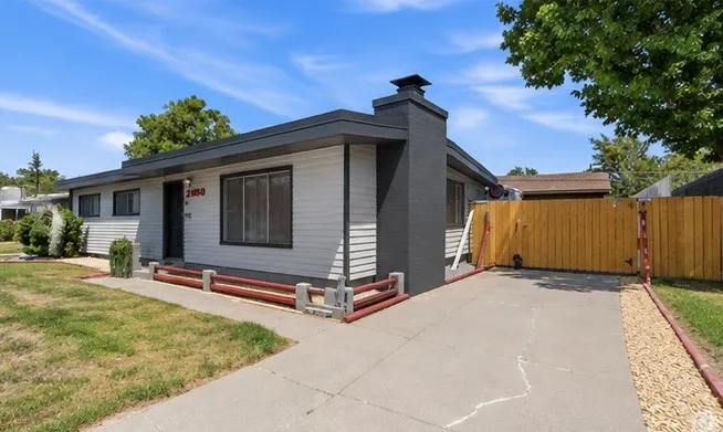 Siding exterior with dark trim accents, concrete driveway, and natural wood fencing