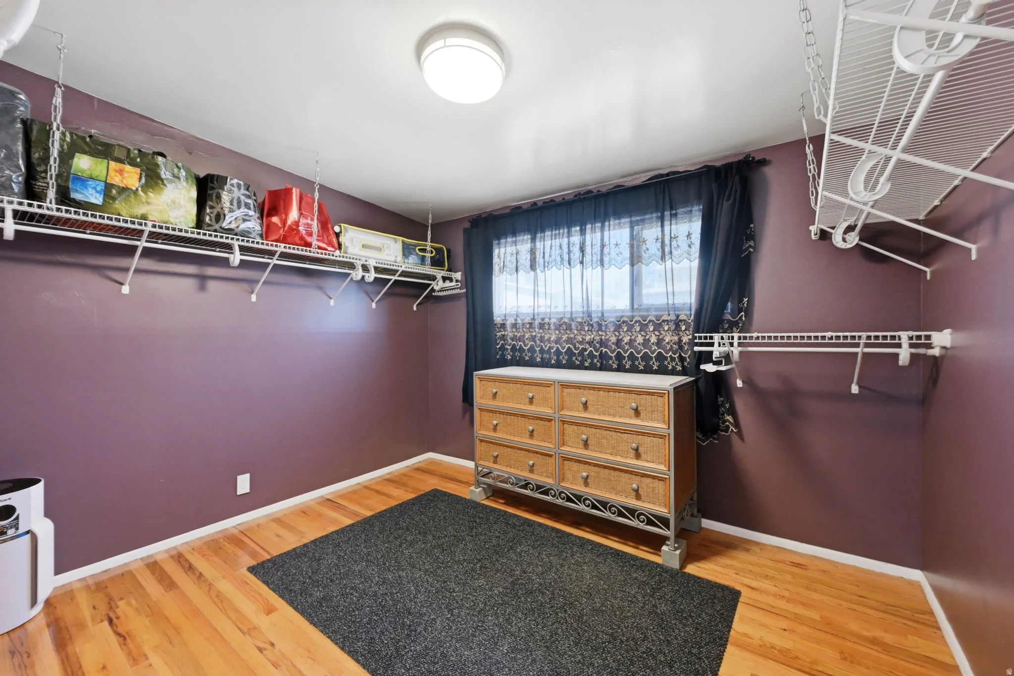 Hardwood-style flooring, white wire shelving systems, and a flush-mount ceiling light