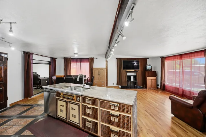 Kitchen island with built-in stainless steel dishwasher, double basin sink, and mosaic-style cabinetry