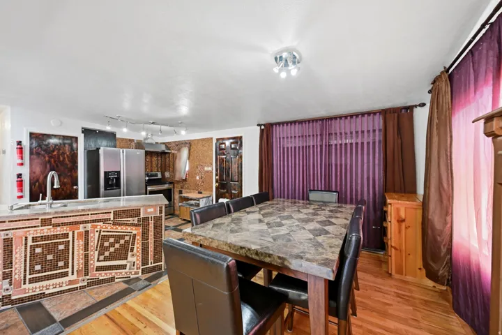 Kitchen island with tile-finish facade, stainless steel appliances, and a dining area featuring hard surface flooring