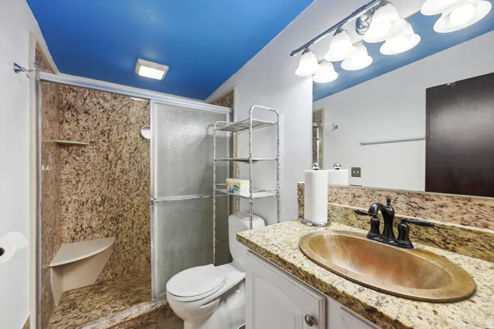 Bathroom featuring a vanity with a copper-finish sink, dark bronze-finish faucet, and granite countertop