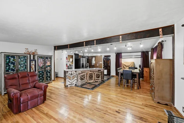 Hardwood flooring throughout, kitchen island with integrated sink, recessed lighting, and a dining area