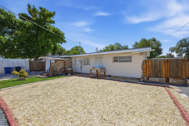 Spacious gravel courtyard with mature landscaping and wooden privacy fencing