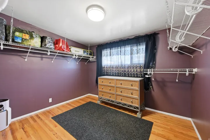 Hardwood-style flooring, white wire shelving systems, and a flush-mount ceiling light